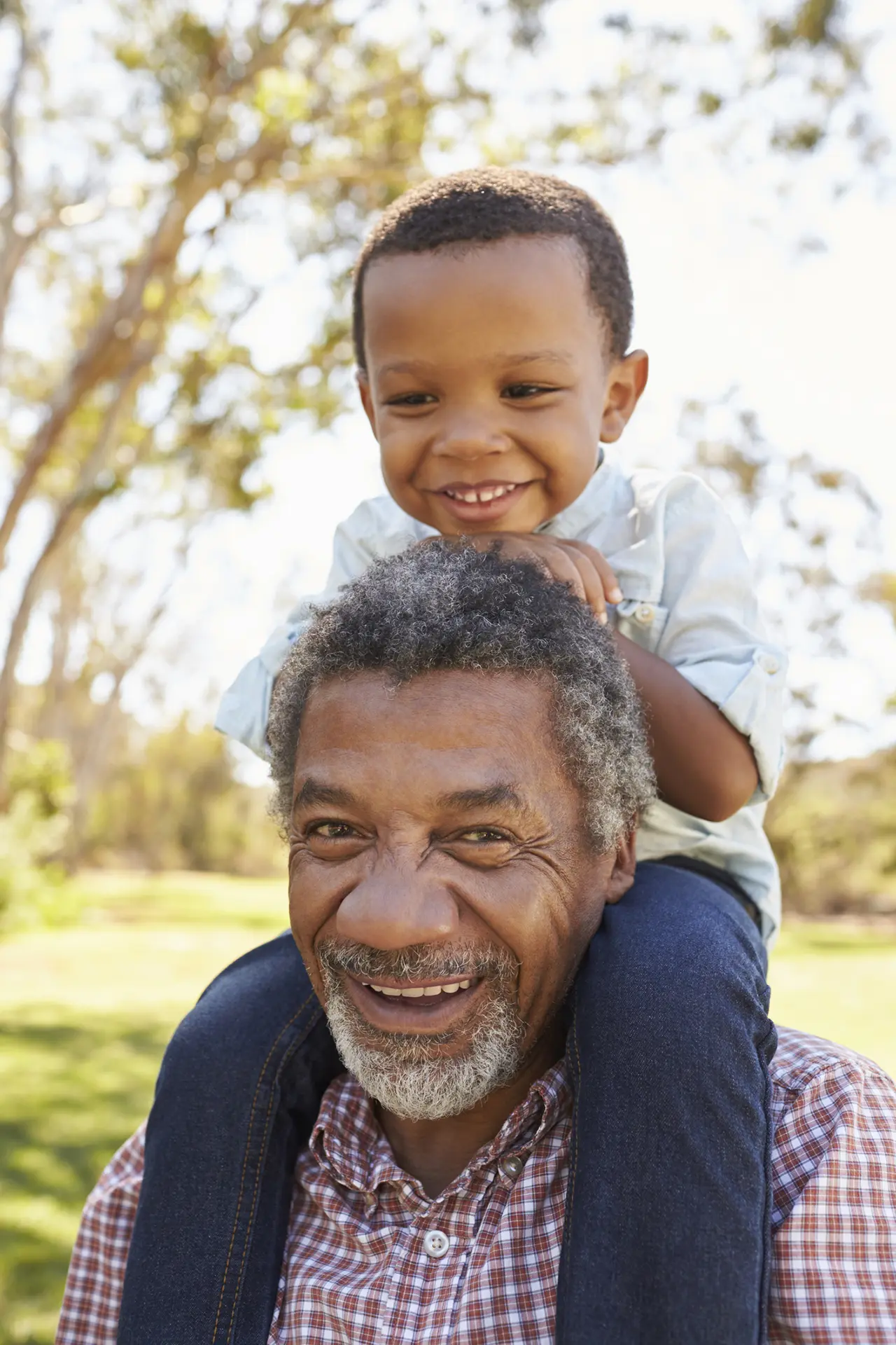 Black grandfather with his grandson on his shoulder laughing